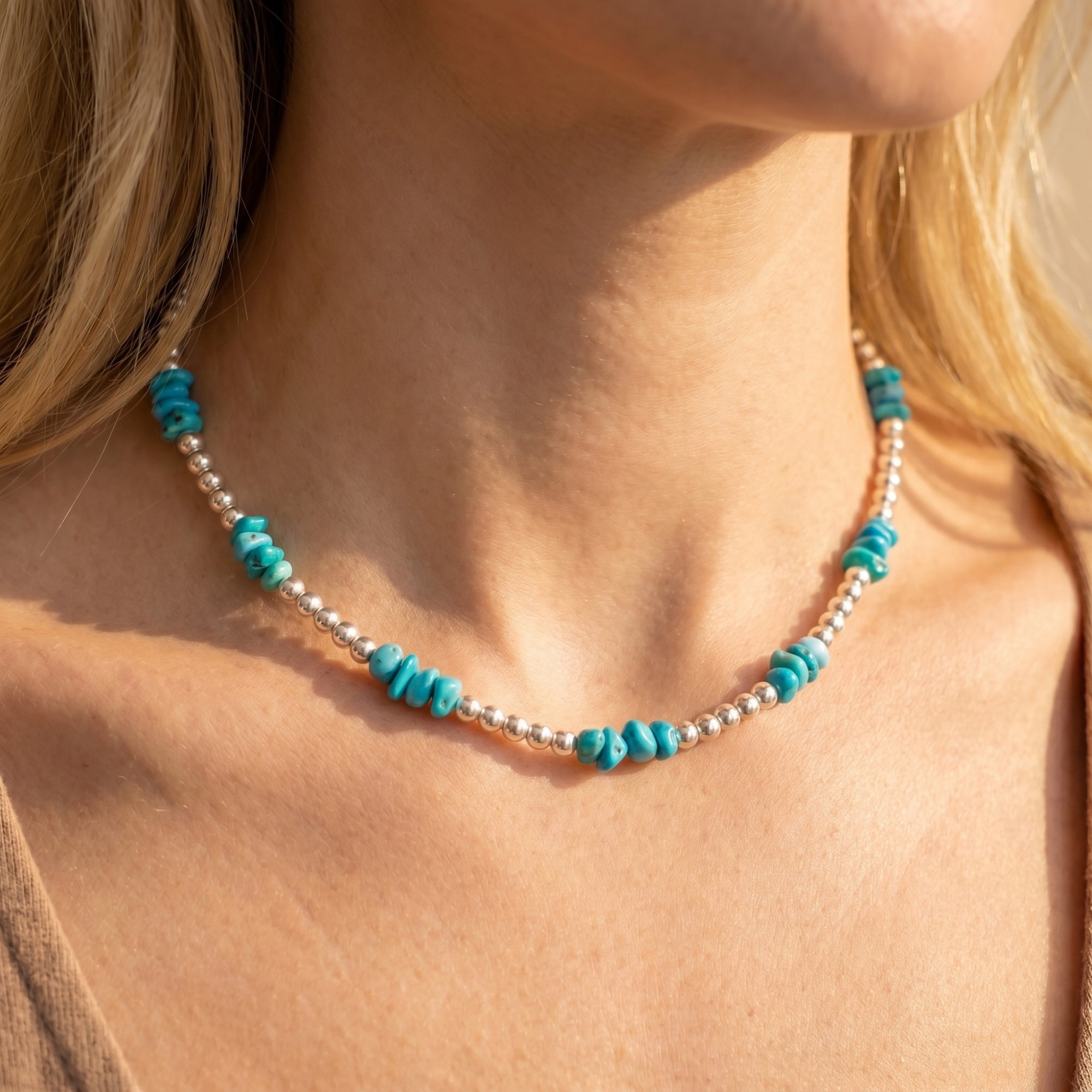 Silver bead necklace with turquoise accents worn by a model, showing the fit on the neck.