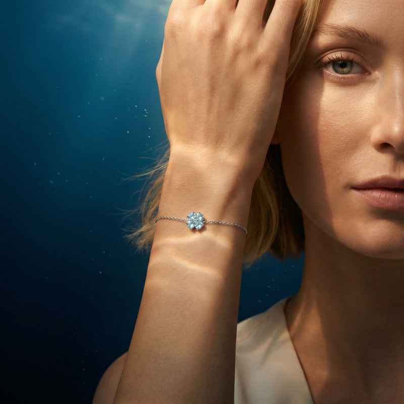 Heart-cut aquamarine station bracelet in platinum worn on a woman's wrist with aquatic light effects.
