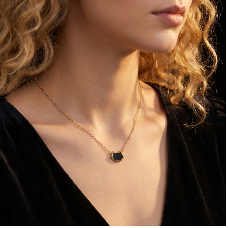 The Umbra Onyx Necklace in 18K gold plating with an irregular-cut black onyx pendant, worn by a model.