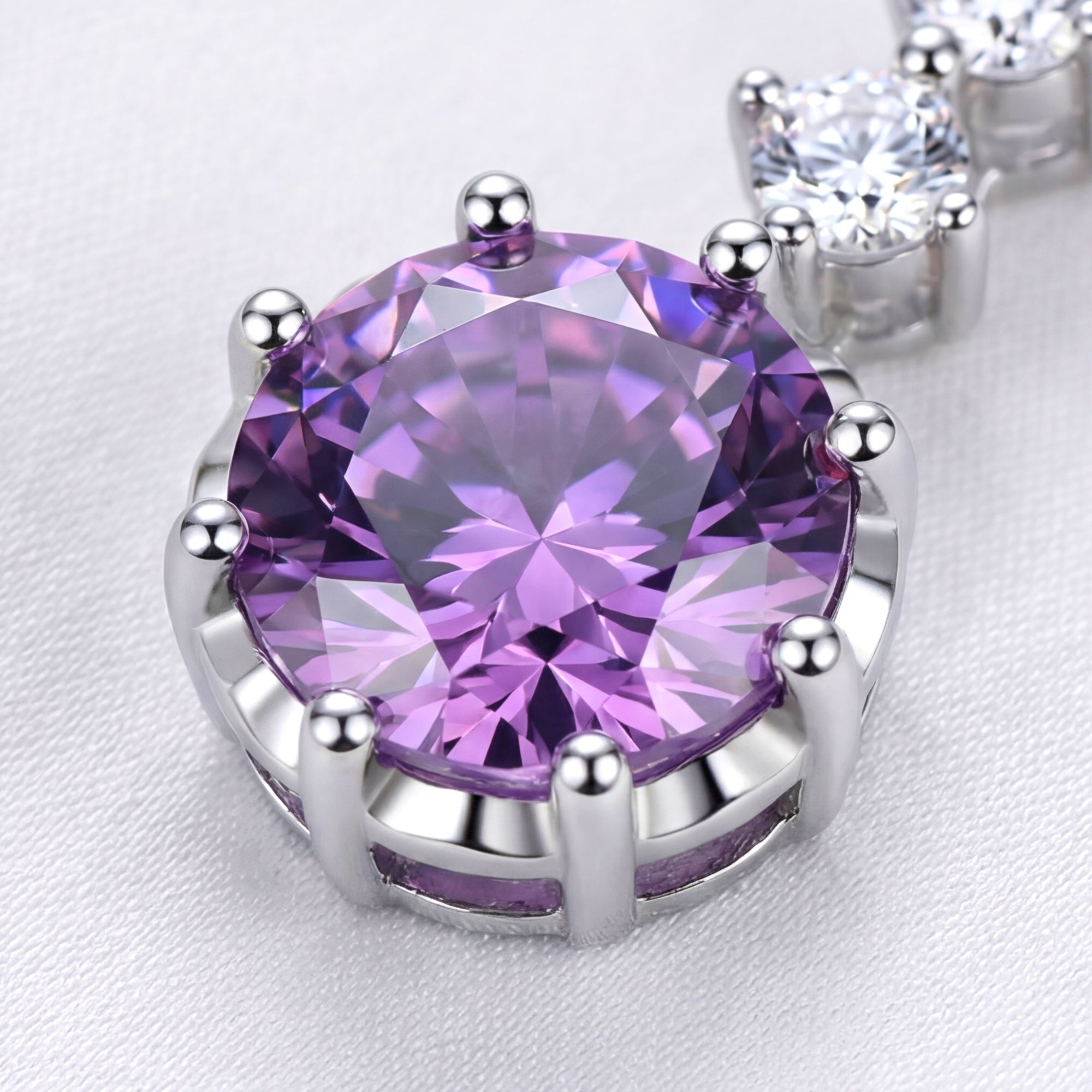 Macro view of a round purple simulated amethyst in a multi-prong sterling silver setting.