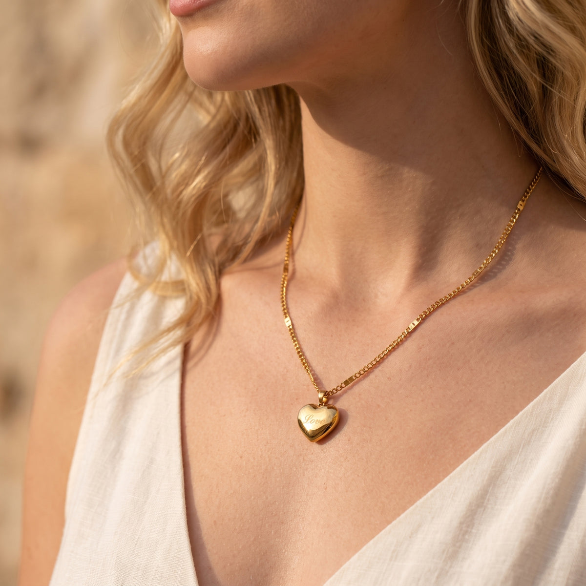 Model wearing the gold-tone Love heart pendant necklace with a white top.