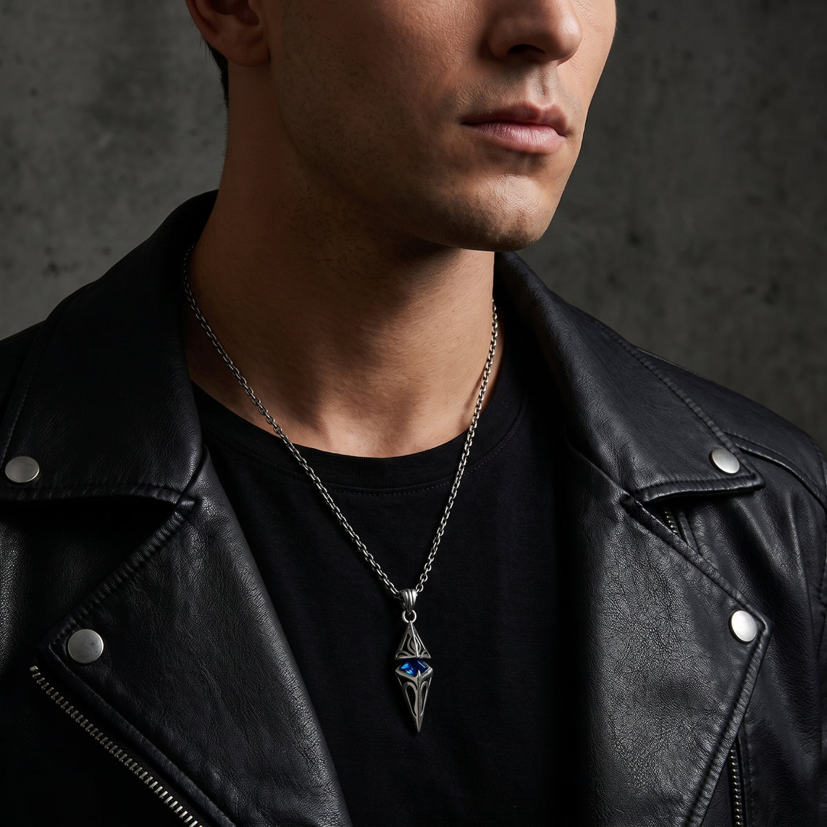 Man wearing the silver pendant necklace with a blue center stone over a black shirt and leather jacket.
