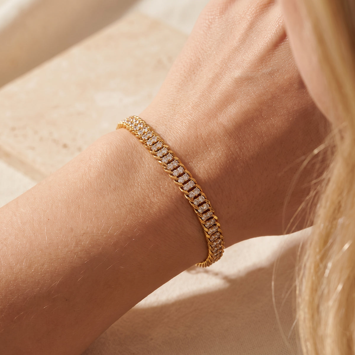 Close-up of a gold-tone double-row pavé link bracelet worn around a wrist.
