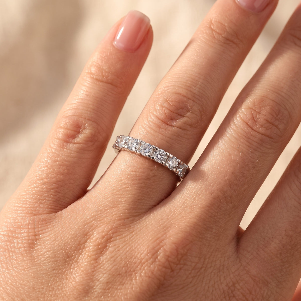 Close-up of the Evadienne silver eternity ring with brilliant round-cut simulated diamonds worn on a woman's finger.