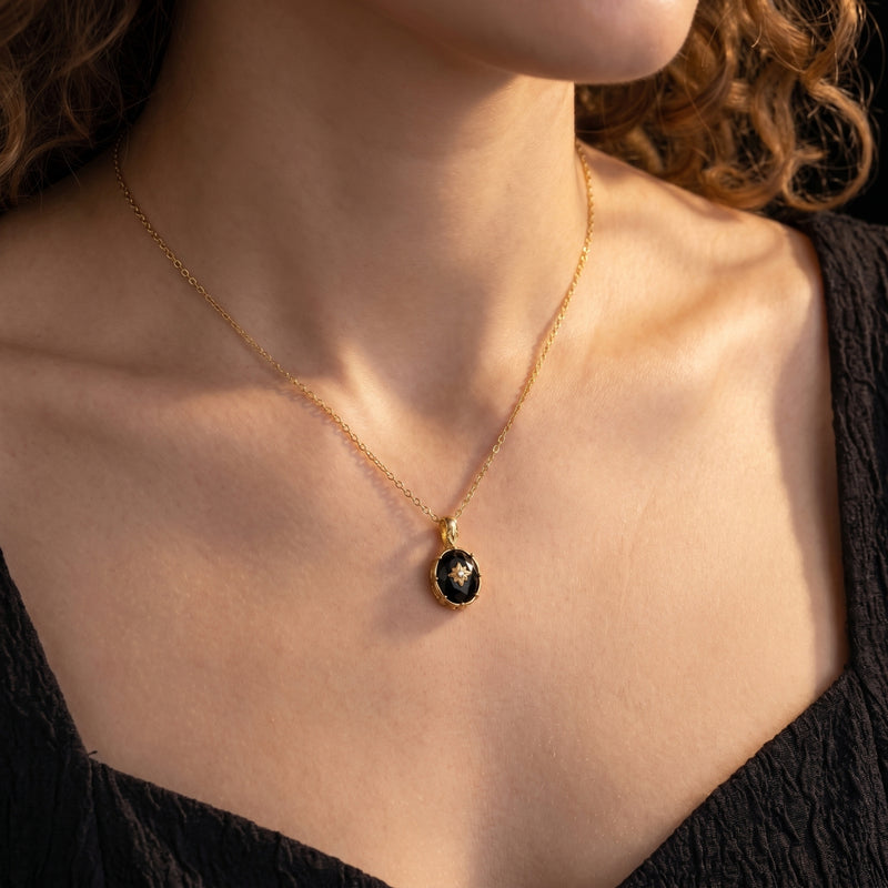 Model wearing the Monarch oval-cut black onyx pendant necklace in 18K gold plating against a black dress.