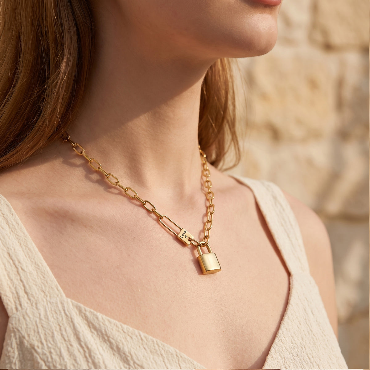 Gold-tone padlock link necklace worn around the neck, shown from a side angle.