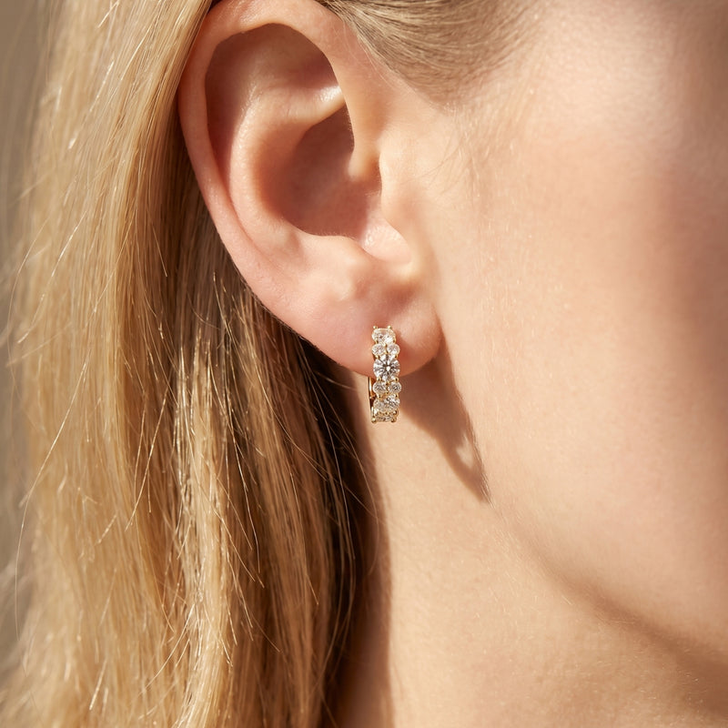 Yellow gold moissanite hoop earring worn on a model's ear.