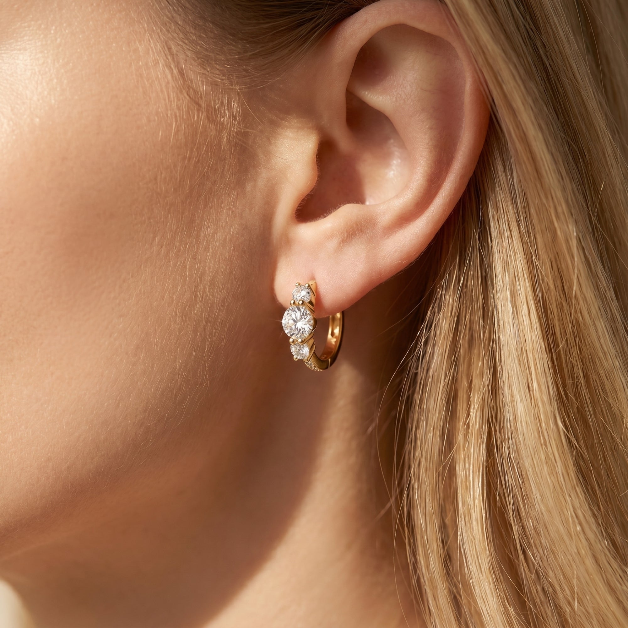 Woman wearing a gold moissanite hoop earring with round-cut stones.