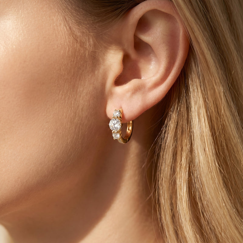 Woman wearing a gold moissanite hoop earring with round-cut stones.