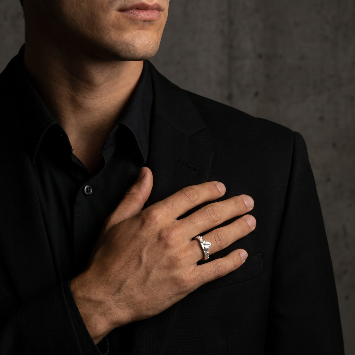 Man wearing the silver mountain ridge ring on his finger while holding his hand over his chest.