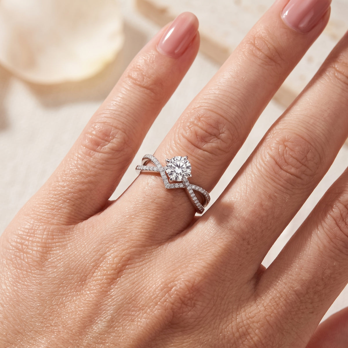 Close-up of a hand wearing the silver infinity solitaire ring featuring a round center stone and pave band.