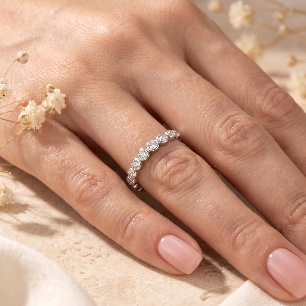 Silver bezel-set eternity ring worn on a hand's ring finger.