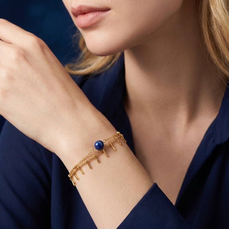 Dainty 18K gold plated lapis lazuli bead bracelet worn on a woman's wrist with a navy blue shirt.