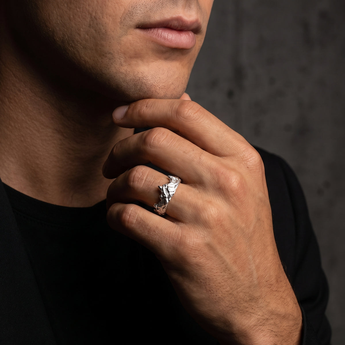 Model wearing the silver mountain crest ring while resting his hand beneath his chin.