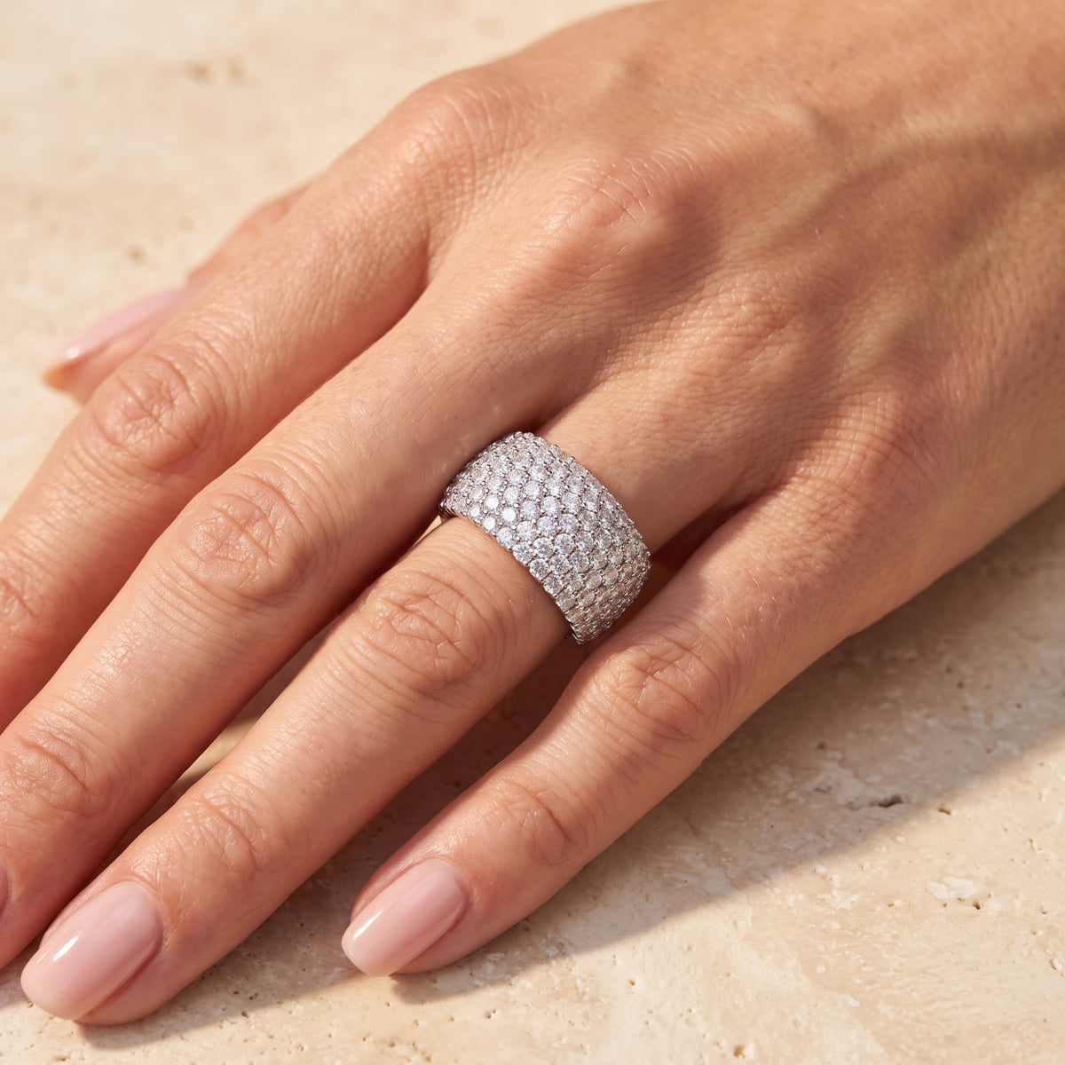 Top-down view of a hand wearing the wide silver cobblestone pave ring on a finger.