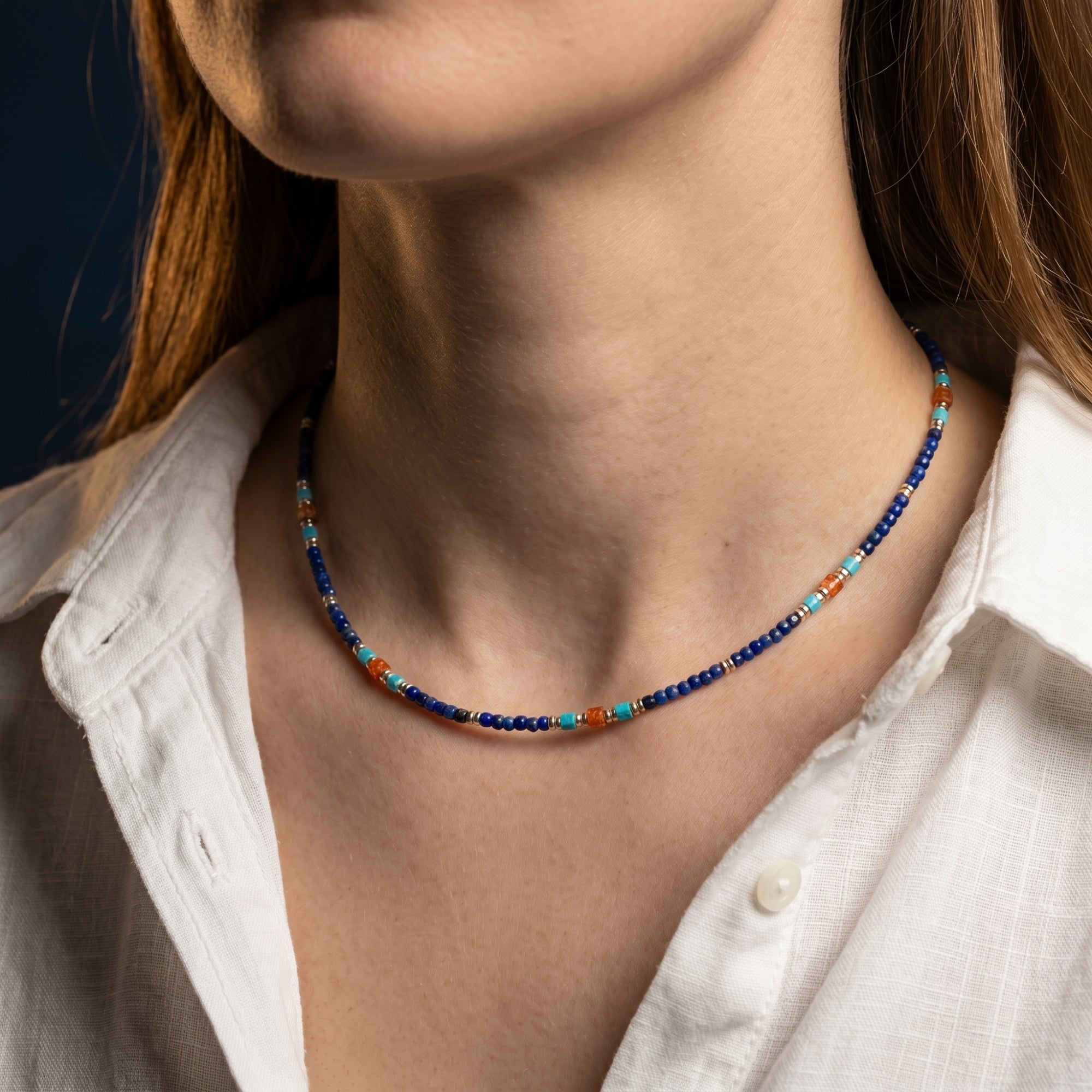 Starfall beaded necklace with 5mm lapis, turquoise, and orange beads and gold spacers worn by a model.