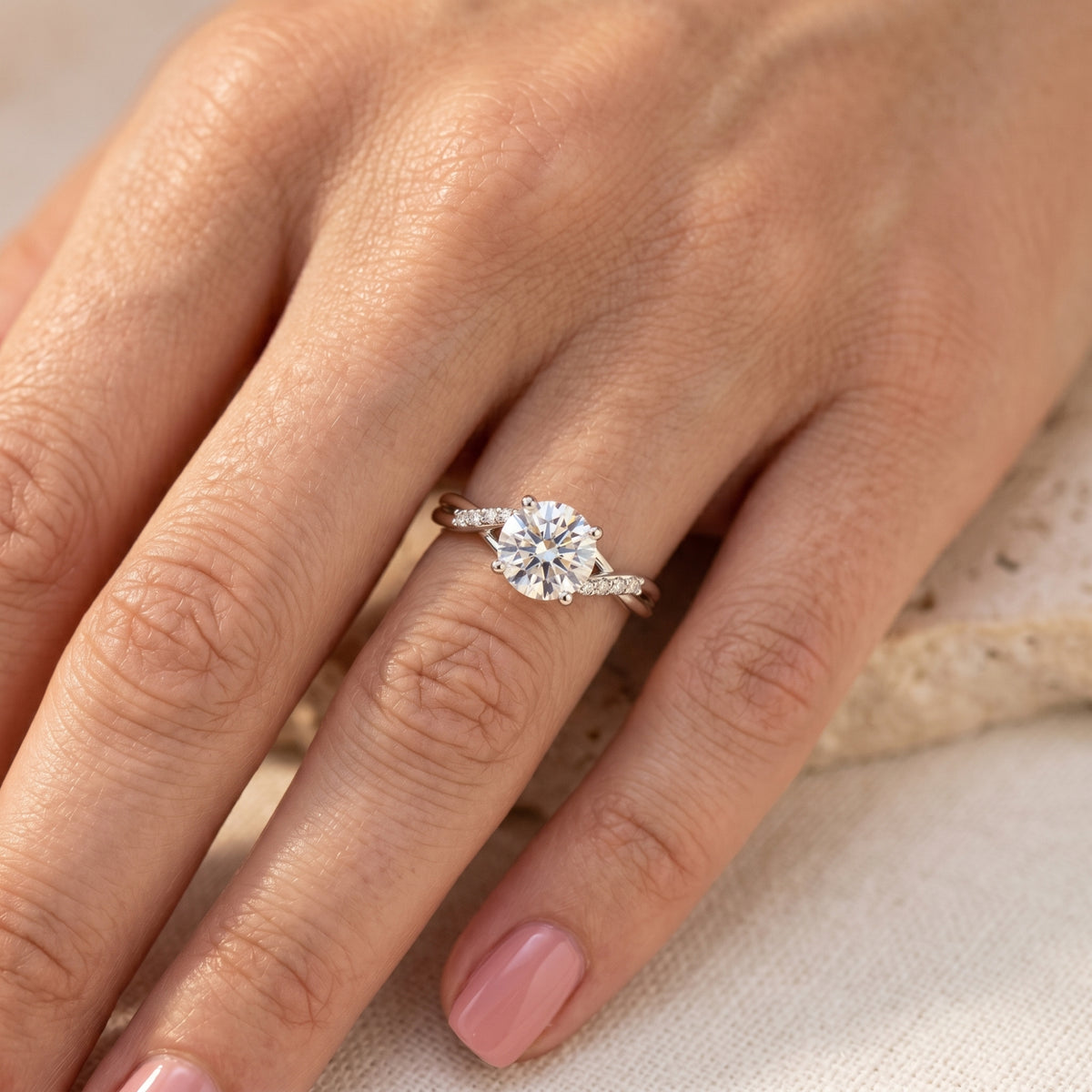 Round cut moissanite ring in silver worn on a woman's finger.
