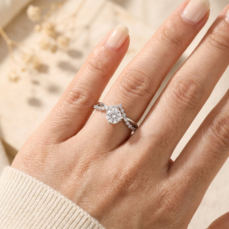 Close-up of the silver Caladienne ring with a round-cut moissanite and arched crown design worn on a woman's finger.