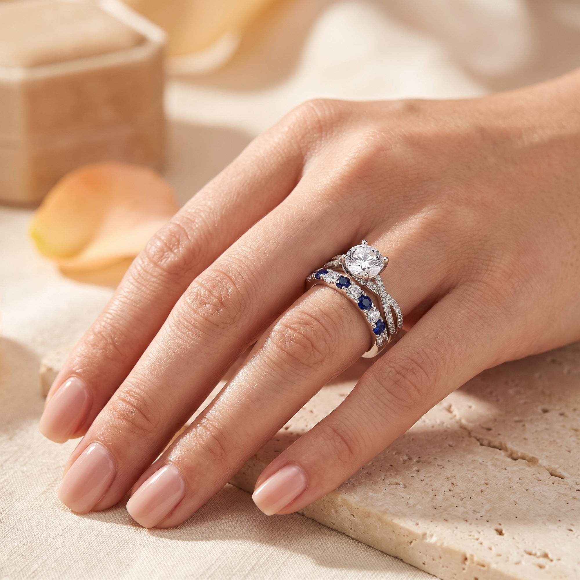 Sterling silver Fiona ring set with round solitaire and blue stone band worn on a hand.