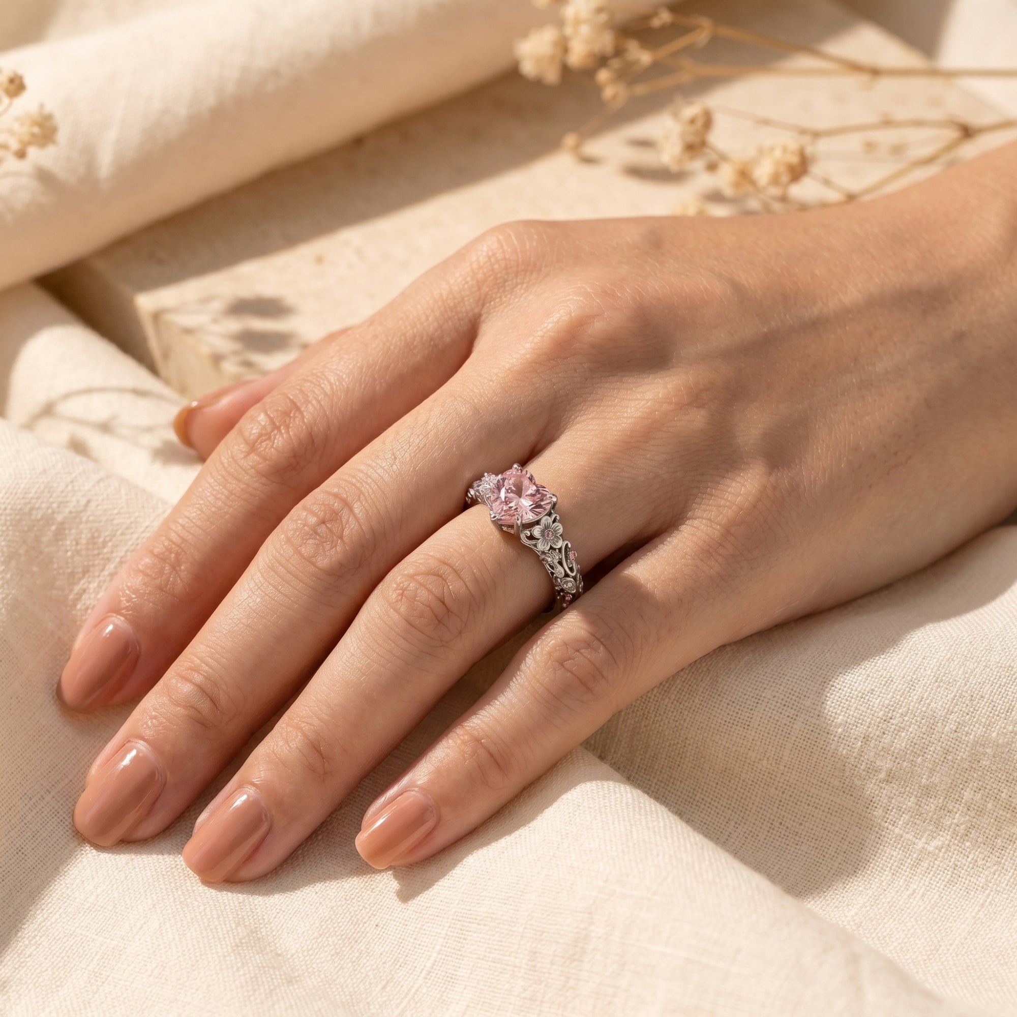 Heart-cut pink diamond silver ring on a woman's hand.