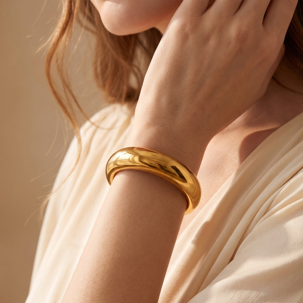 Model wearing the high-polish gold-toned sculpted dome cuff bracelet on her wrist.