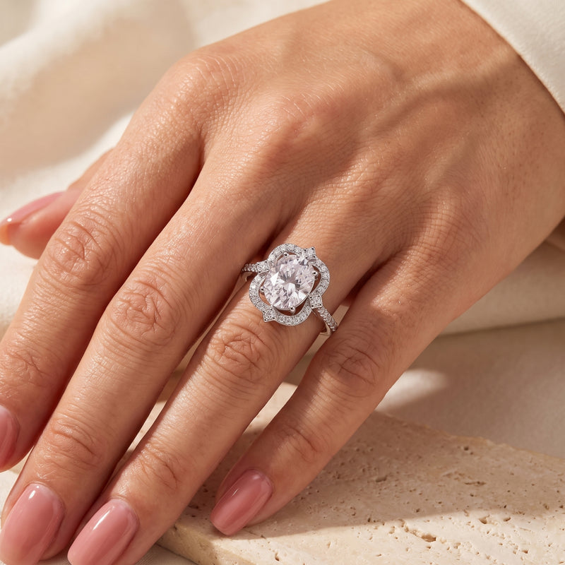 Silver scalloped halo ring with an oval stone, worn on a hand.