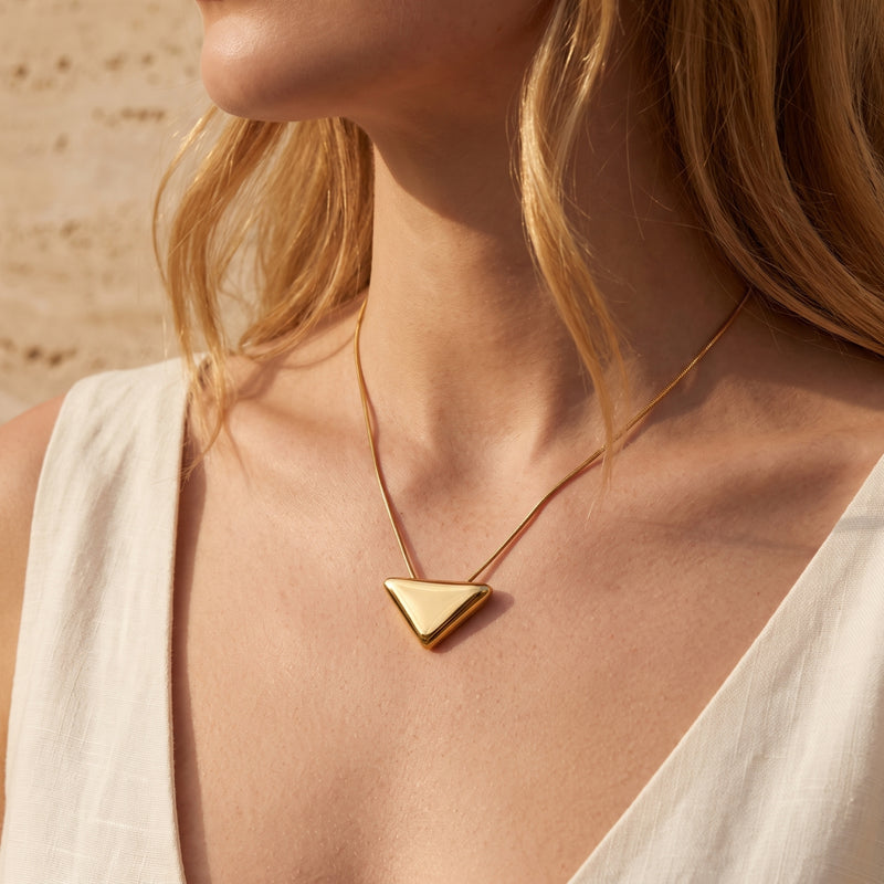 Front view of a model wearing the gold-tone inverted triangle pendant necklace.