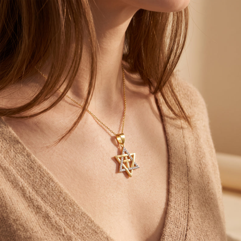 Model wearing a gold-tone Star of David cross pendant necklace over a beige knit cardigan.