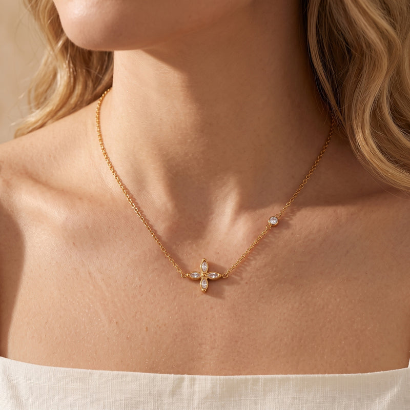 On-model view of the gold-tone four-petal flower necklace resting at the collarbone.