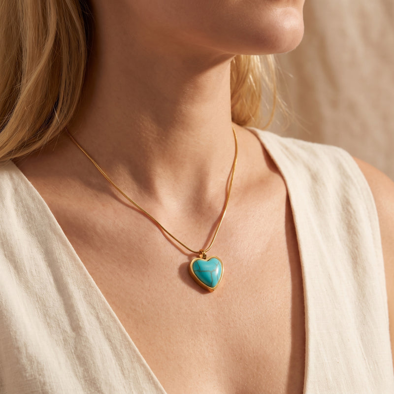 Close-up of a model wearing the gold-tone snake chain and heart-shaped turquoise pendant.