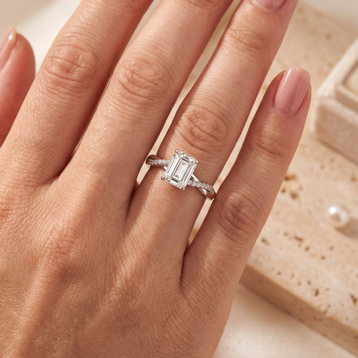 Sterling silver emerald cut CZ promise ring with a twisted band worn on a woman's finger.