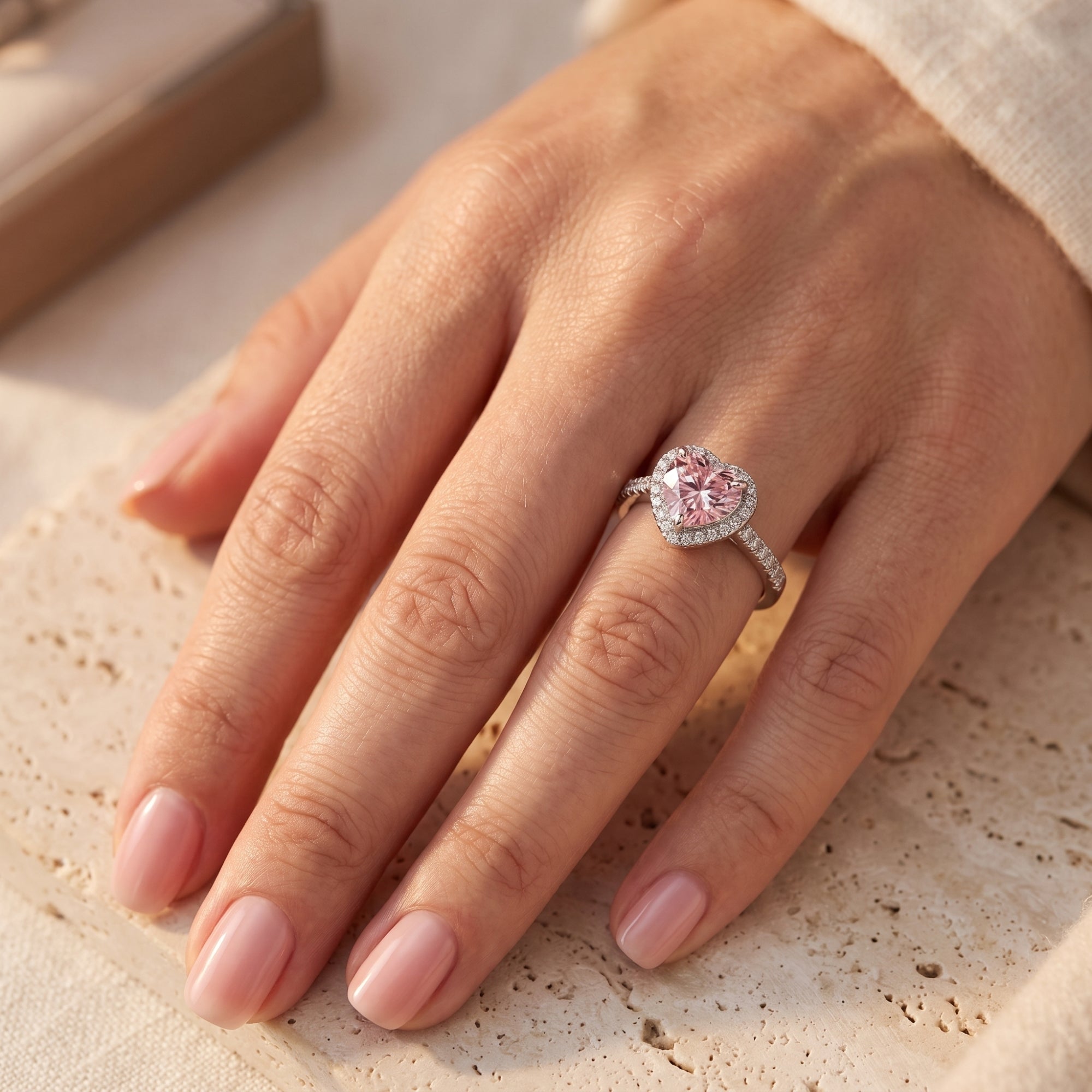 The Amourette heart-shaped simulated pink tourmaline halo ring in sterling silver shown on a woman's finger.