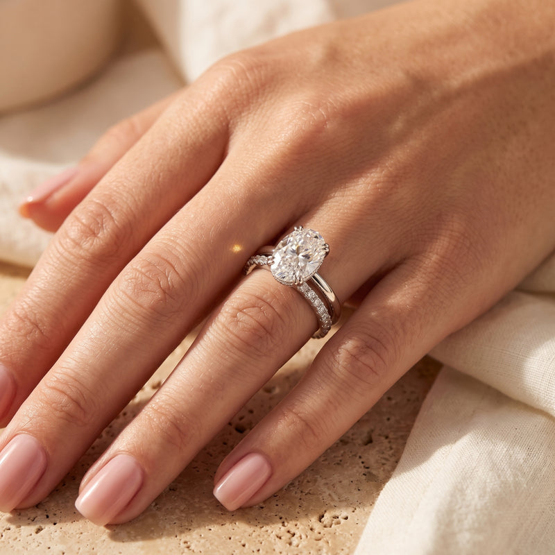Sterling silver oval-cut simulated diamond bridal set worn on a finger.