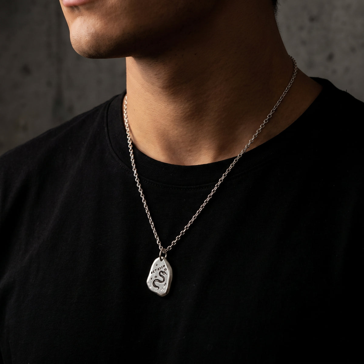 Close-up of a model wearing the silver snake necklace over a black T-shirt.