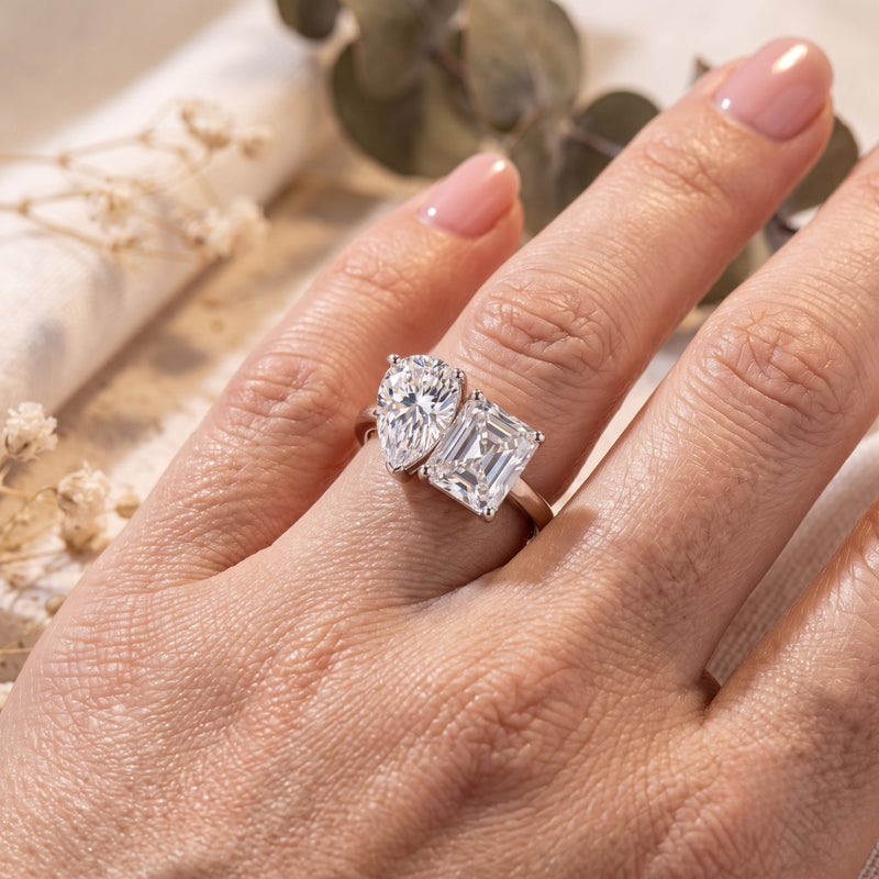 Sterling silver Corentine ring with pear and radiant simulated diamonds worn on a hand.