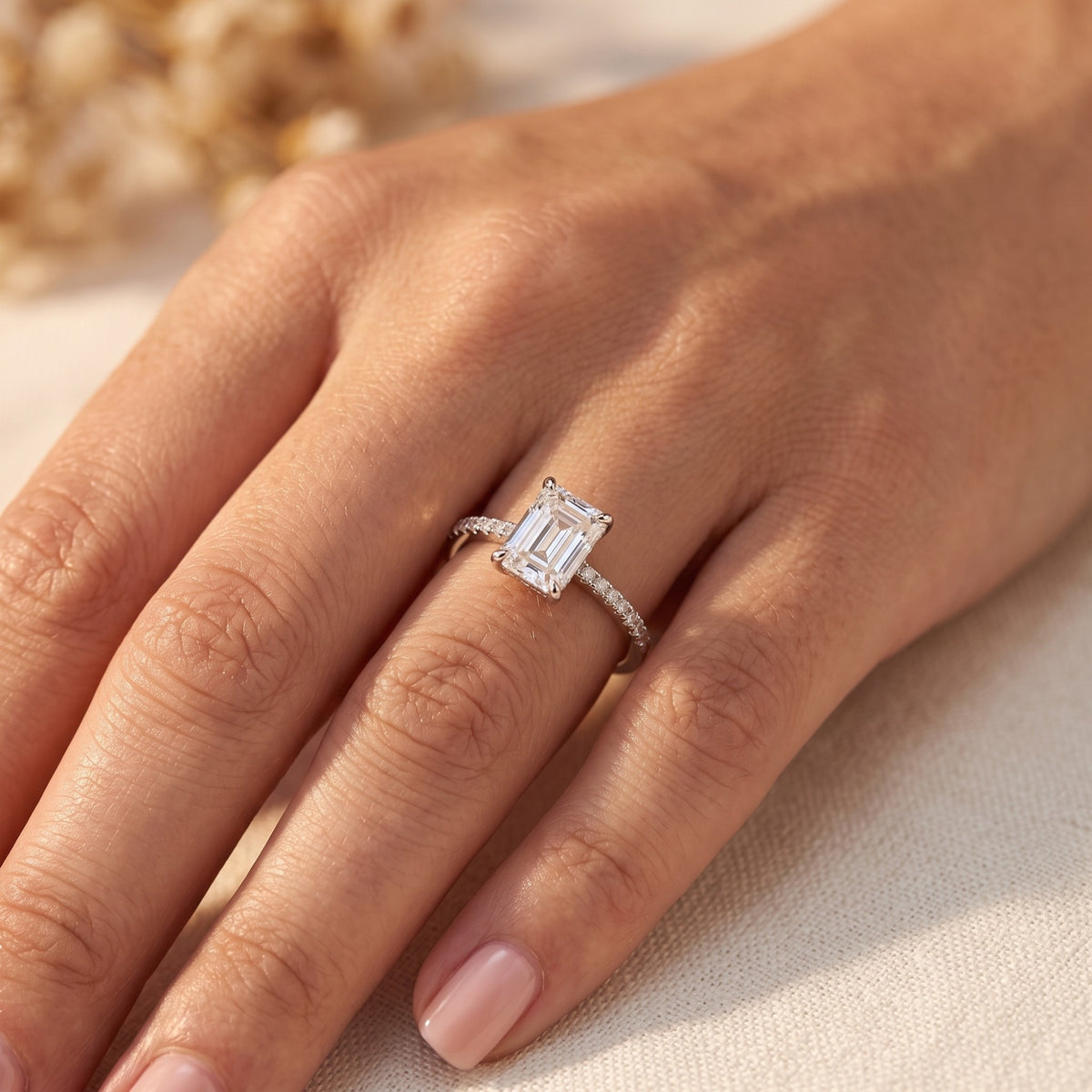 Emerald-cut simulated diamond solitaire ring in sterling silver worn on a woman's hand.