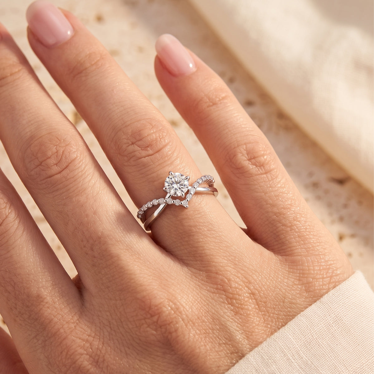 Silver criss-cross chevron split band ring with a round center stone worn on a finger.