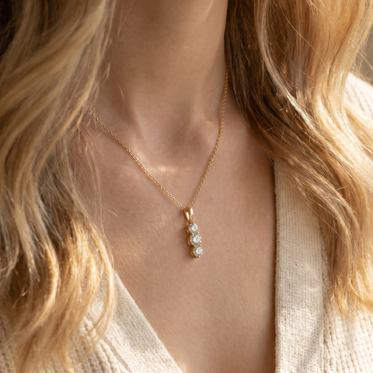 Woman wearing the gold Larisa moissanite pendant necklace with three vertical round stones.