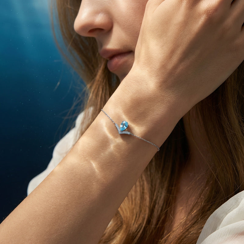 Pear-cut natural aquamarine Pt950 platinum bracelet with diamond accents worn on a woman's wrist, profile view.
