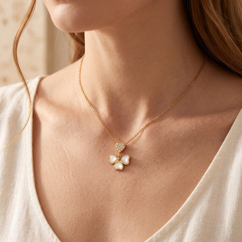 Model wearing a gold-tone mother-of-pearl butterfly necklace with a pavé heart pendant over a light top.