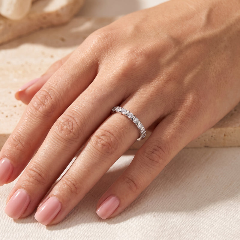 Full-hand view of a silver bar-set ring with round clear stones worn on a finger.