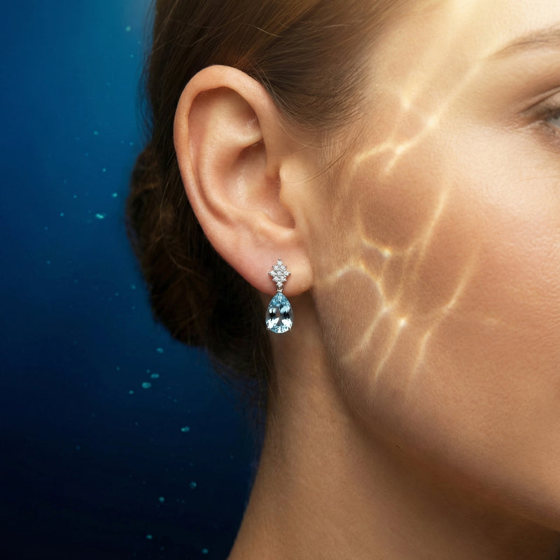 Woman wearing a pear cut aquamarine drop earring in platinum, showing the scale and sparkle on the ear.