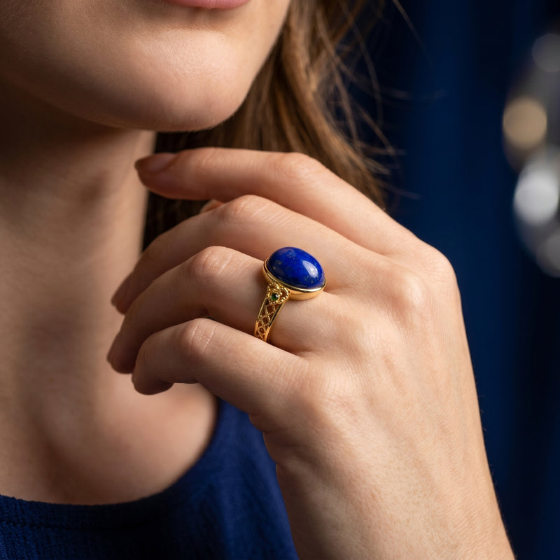 Woman wearing the yellow gold lapis lazuli ring with an oval cabochon gemstone and intricate lattice band.
