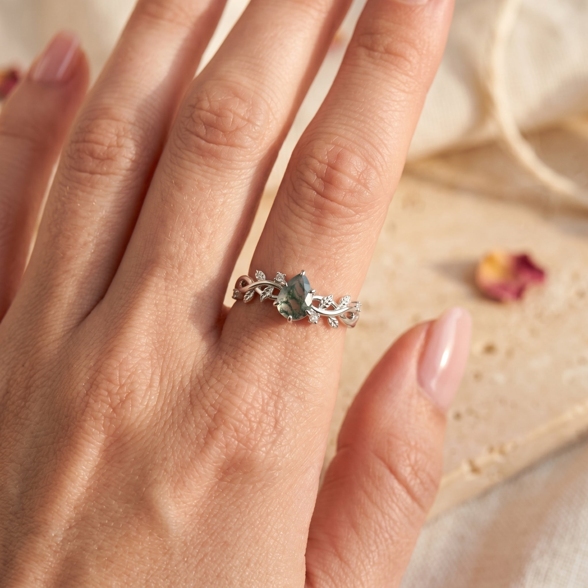 Pear-cut moss agate promise ring in sterling silver worn on a finger.