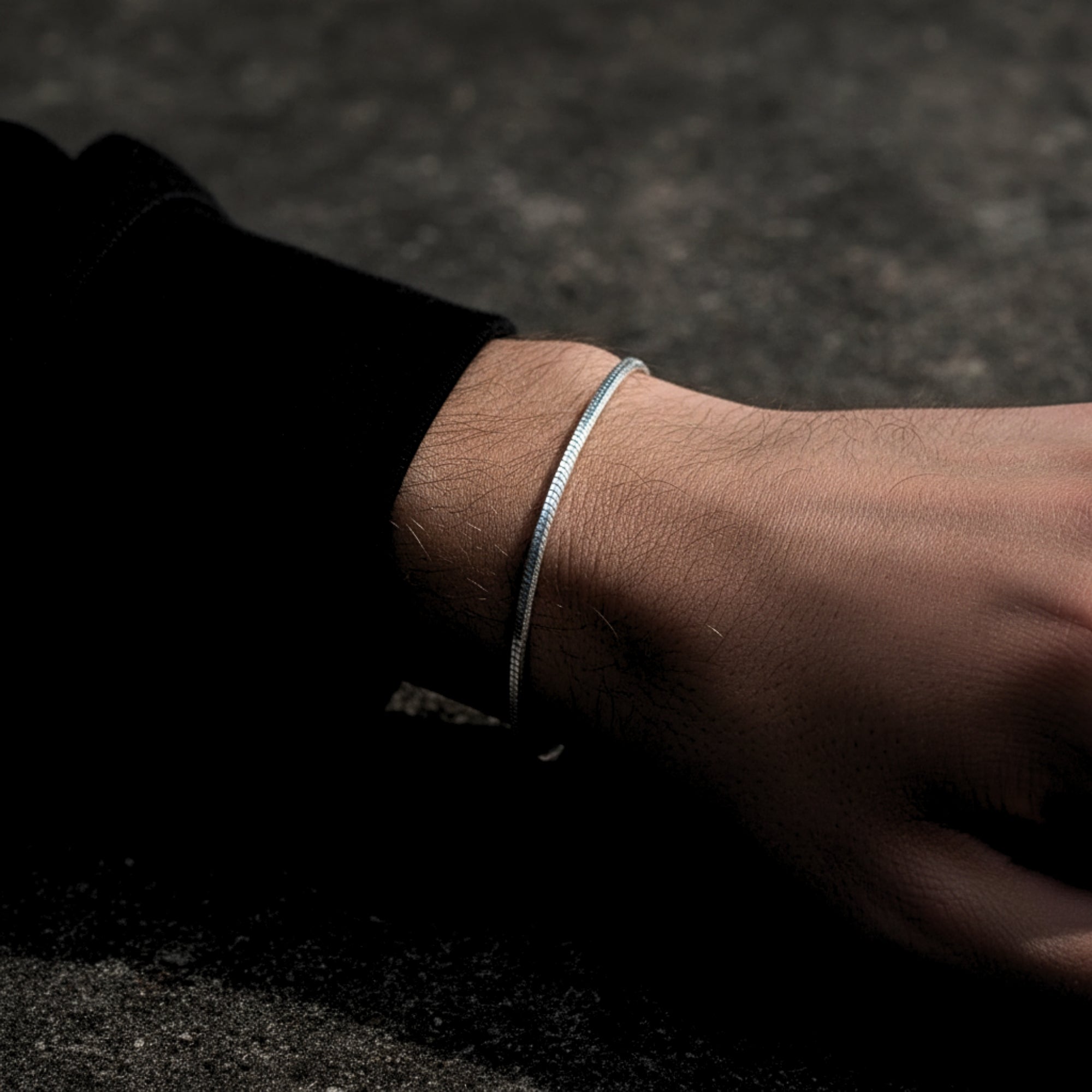Men's silver stainless steel octagon link bracelet worn on a wrist with a black sleeve.