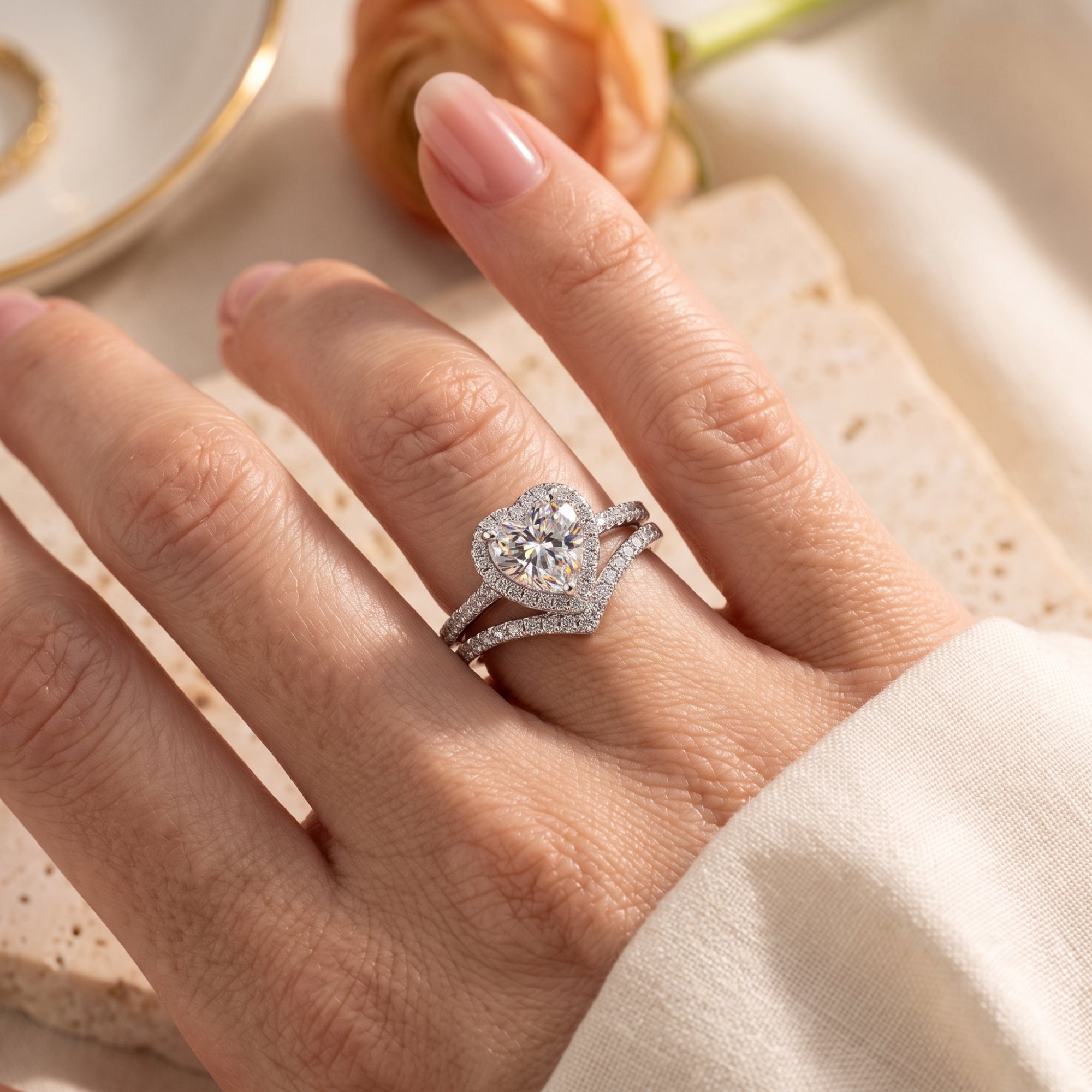 Sterling silver heart halo ring and chevron band worn on a woman's hand.