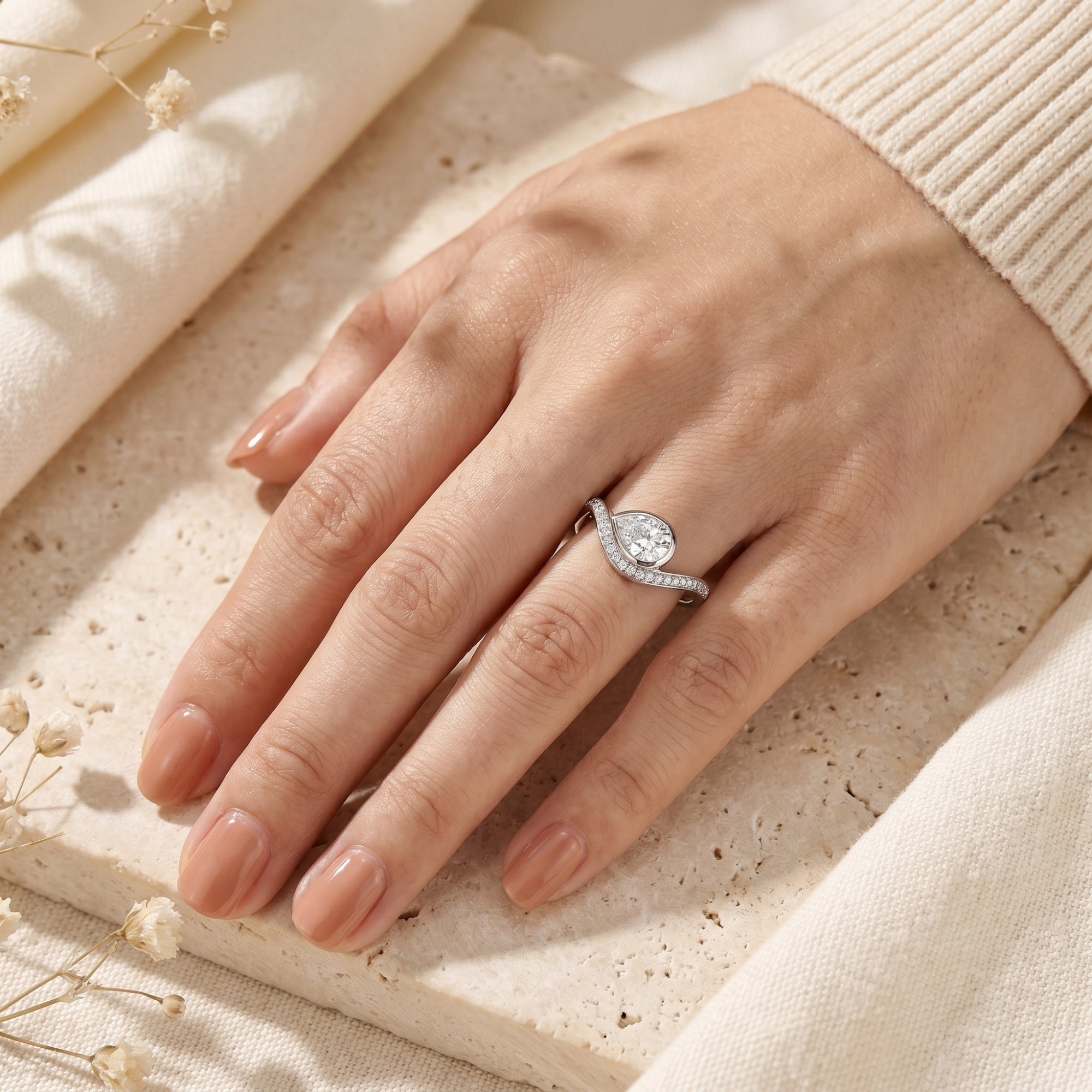 Silver pear moissanite promise ring worn on a woman's hand.
