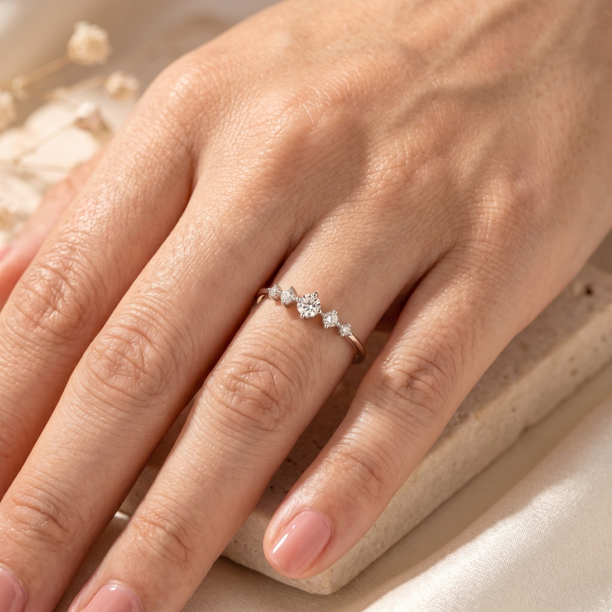 Round moissanite ring in sterling silver worn on a finger.