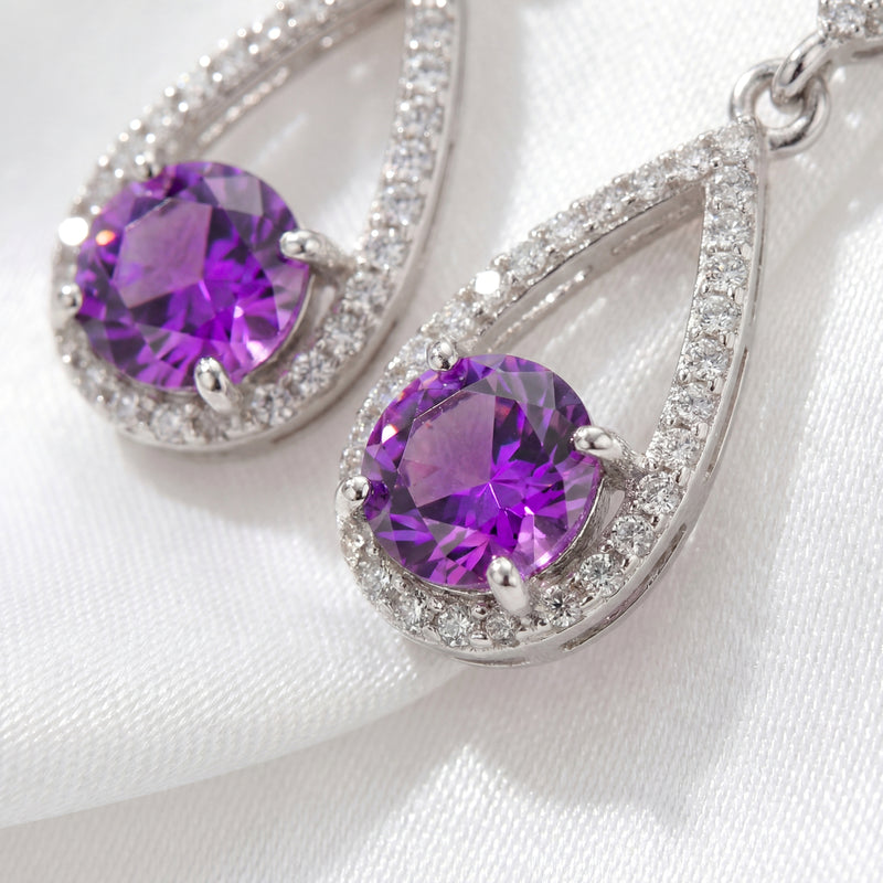 Macro view of round-cut simulated amethyst stones in sterling silver pave teardrop settings.