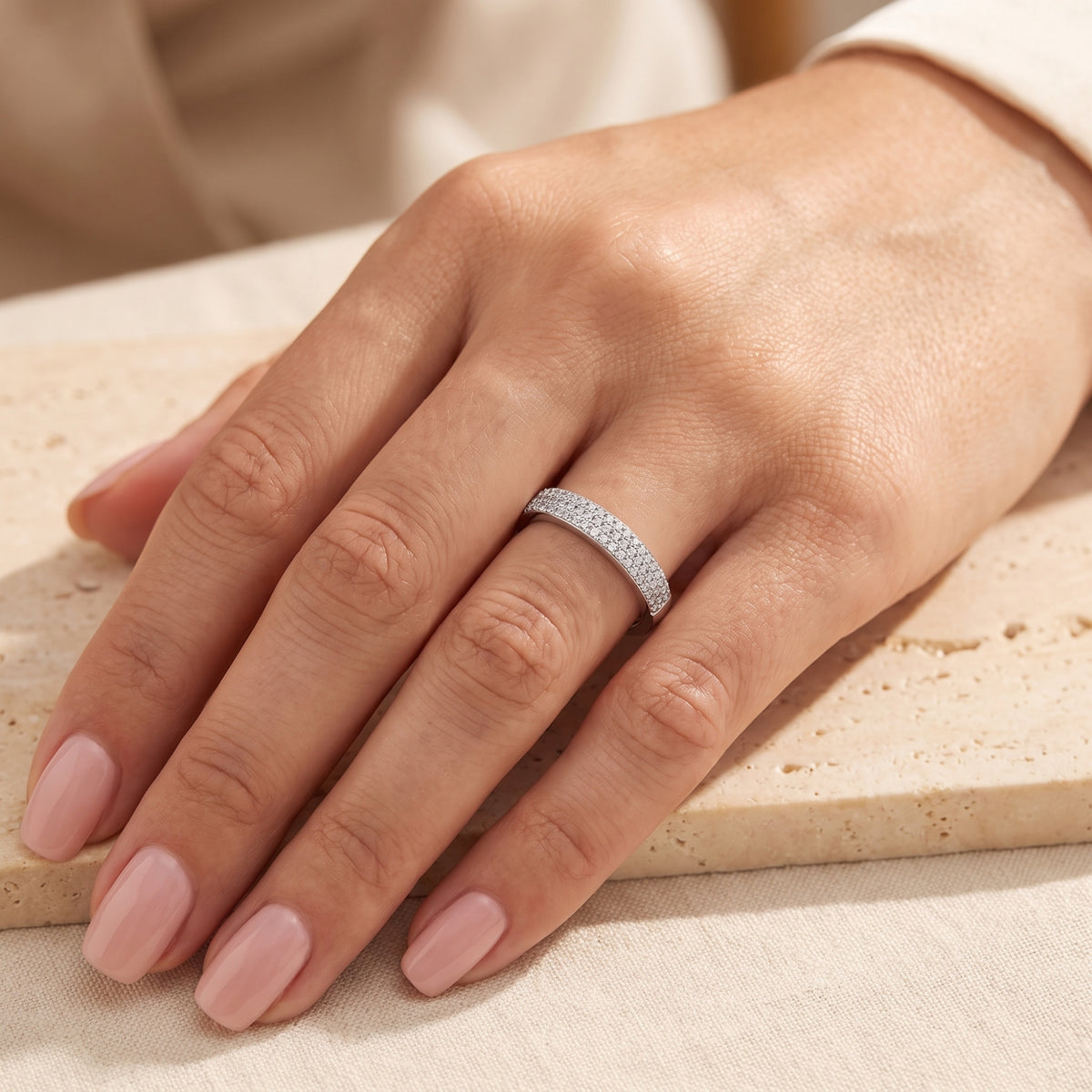 Top-down view of a hand wearing the silver triple-row pavé band ring on the ring finger.